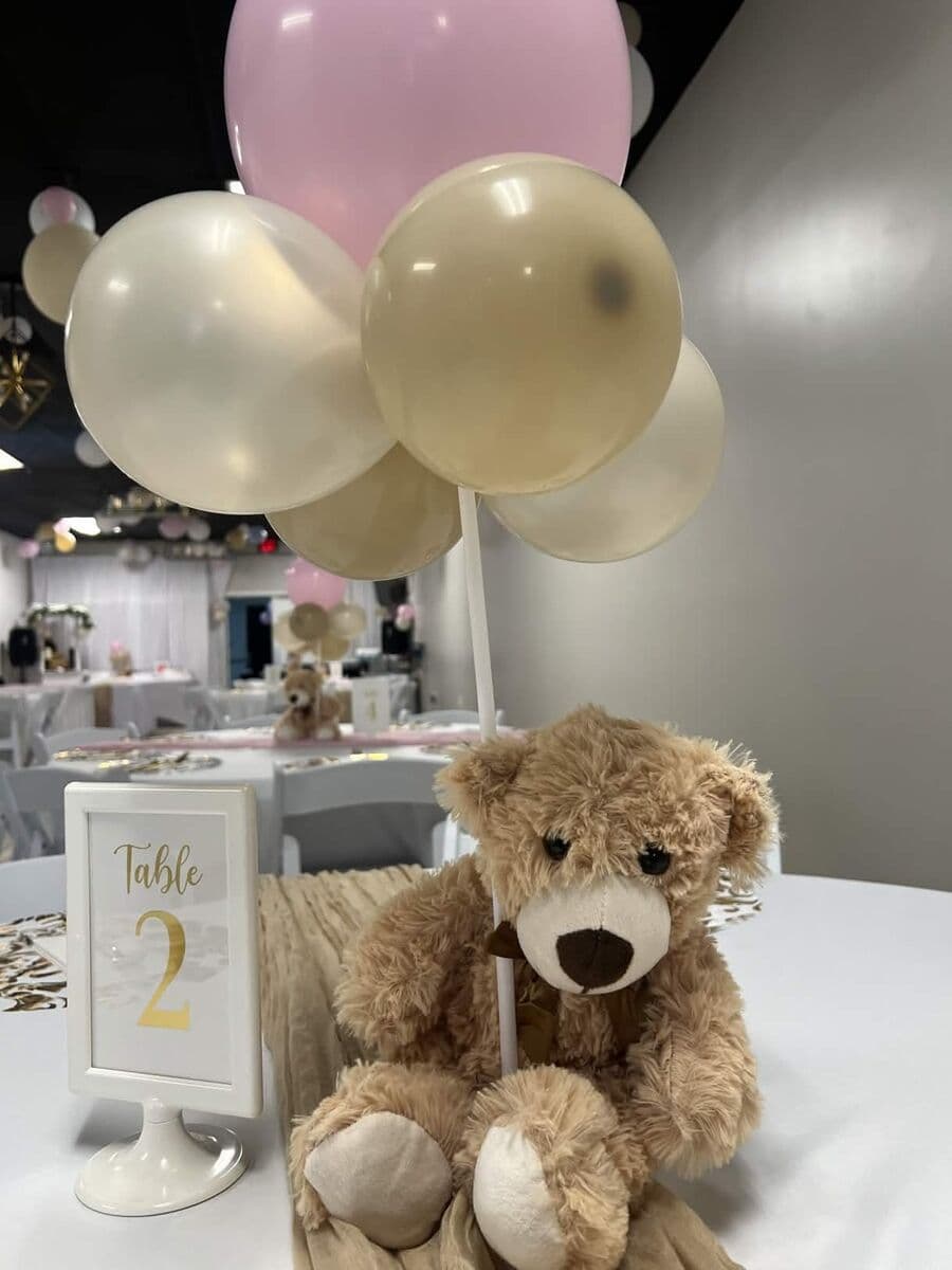 Teddy bear centerpiece with pink and cream balloons and gold table number
