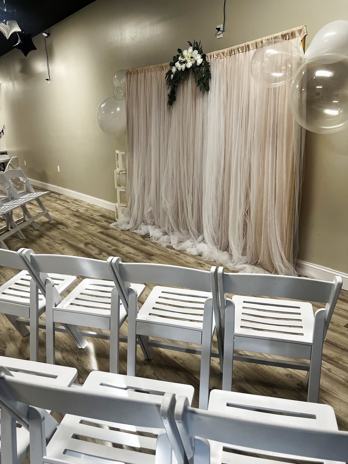 White ceremony chairs and blush backdrop set up for a wedding at LSC Event Space